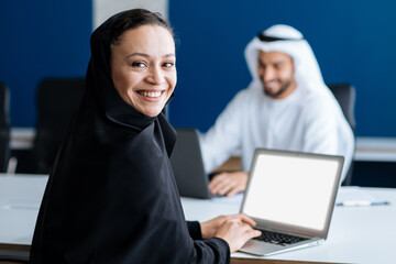 Handsome man and woman with traditional clothes working in an office of Dubai