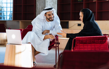 handsome man and woman with traditional clothes working in an office of Dubai