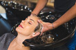 © PoppyPix - Happy blond client having her hair washed with shampoo by hairdresser in a professional hair salon. High quality photo