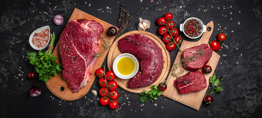 Beef tenderloin fillet with rosemary and spices on a dark background. Preparing fresh beef steak ready to cook, Long banner format. top view