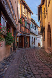 Fototapeta Uliczki - Alley with old half-timbered houses decorated with flowers. Eguisheim, France, Europe