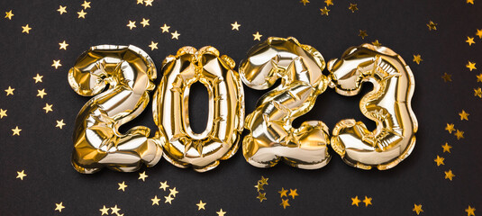 Wall Mural - New year 2023 balloon celebration card. Gold foil helium balloon number 2023 and gold confetti stars isolated on black background. Flat lay, merry christmas, happy holidays mockup.