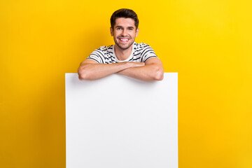 Poster - Photo of cute cheerful man wear white t-shirt holding hands arms empty space isolated yellow color background