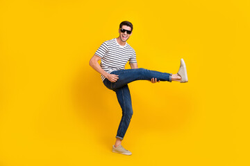 Wall Mural - Full length photo of excited cool man wear white t-shirt dark glasses playing leg guitar having fun isolated yellow color background