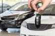 Hand hold a new car key on car background