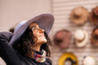 © ADDICTIVE STOCK - Happy woman in hat shop