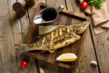 Wall Mural - Fried sea bass on wooden board top view