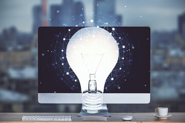Poster - Computer on desktop in office with bulb icon hologram. Multi exposure. Concept of idea.