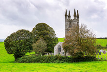 Old Stone Church In Grassy Field Surrounded By Trees And Graveyard In The Background; Cornwall County, England
