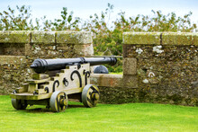 Old Cannon With Wooden Base In Opening On Stone Wall; Cornwall County, England