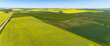 © Designpics - Aerial view of a country road beside flowering canola fields that are standing out next to green fields under a blue sky; South of Three Hills, Alberta, Canada