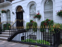 Entrance To Typical White Painted London Townhouse, With Hanging Baskets Of Summer Flowers