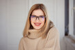© Ulia Koltyrina - Young cute blonde with eyeglasses and a beige sweater. Stylish fashionable young woman. woman with glasses smiling