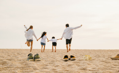 Wall Mural - Happy family day. Back view of Asian having family parents with child fun holding hands together running to beach, lifestyle father, mother and kids relax take off shoes run on sand, holiday travel