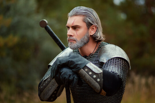 An aged male warrior in chain mail with gray hair and a scar on his face. Knight in armor holds a two-handed sword.