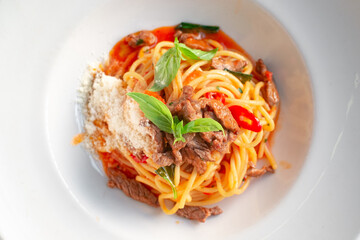 Wall Mural - Spaghetti pasta with tomato sauce and beef stew, tomatoes, parmesan cheese and fresh basil on a wooden background. Italian cuisine, top view