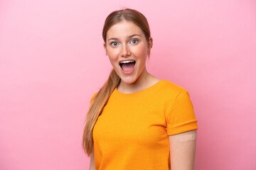 Young caucasian woman wearing band aid isolated on pink background with surprise and shocked facial expression