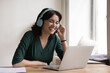© fizkes - Happy freelancer professional woman in big bright headphones talking on video call, speaking at laptop, smiling, laughing, enjoying online communication. Freelance employee listening to music