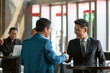 © amorn - Two Asian businessman shaking hands together and congratulation with successful partnership