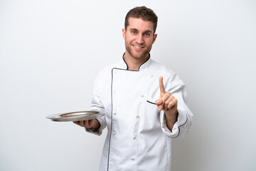 Wall Mural - Young caucasian chef with tray isolated on white background showing and lifting a finger