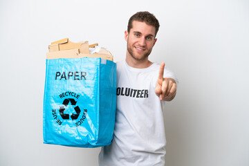 Wall Mural - Young caucasian man holding a recycling bag full of paper to recycle isolated on white background showing and lifting a finger