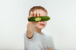 A little boy eats a fresh green cucumber.