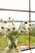 Bouquet with daisies in a vase on a wooden window.