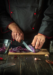 The chef cuts red cabbage with a knife. Cooking vegetable salad in the restaurant kitchen. The idea of a vegetable diet.