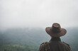 © arrowsmith2 - Freedom traveler man in hat carrying a backpack stands at the top of a mountain on a foggy day.Adventure travel and success concept