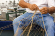 © Fernando - fishing net in the hands of a fisherman, preparing gear to go out to sea, in the background the Mediterranean coast