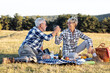 © pucko_ns - Mature couple sitting on blanket in nature and make picnic. She feed old man with piece of food and smile