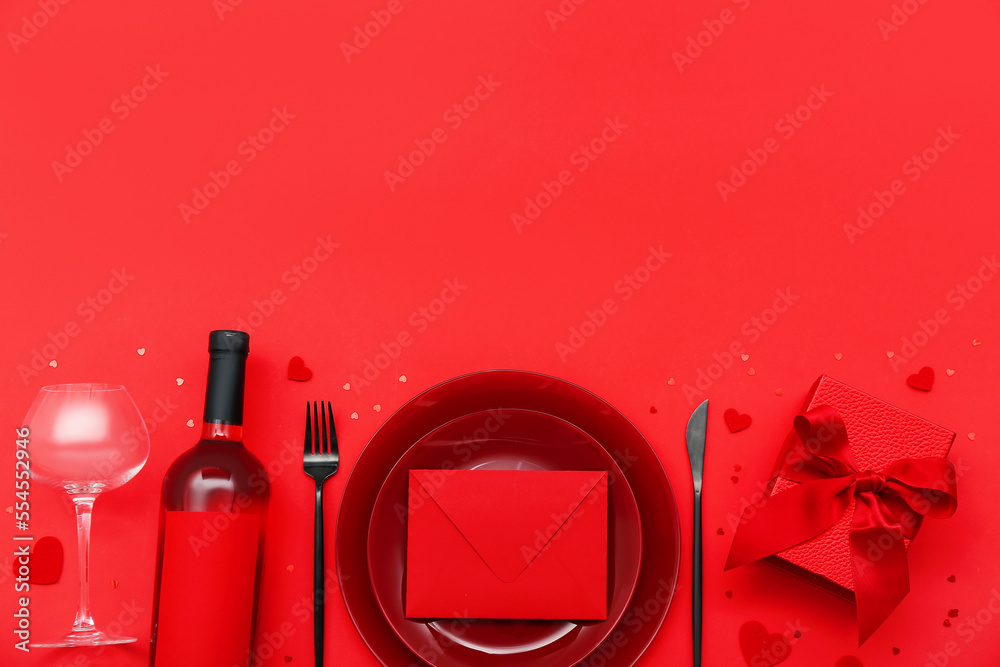 Table setting for Valentine's Day with envelope and gift on red background