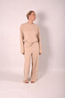 © Шамиль Алиев - A young girl in beige home clothes on a white background in the studio