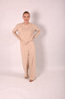 © Шамиль Алиев - A young girl in beige home clothes on a white background in the studio