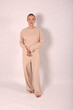 © Шамиль Алиев - A young girl in beige home clothes on a white background in the studio