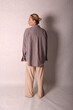 © Шамиль Алиев - A young girl in beige home clothes on a white background in the studio is standing with her back