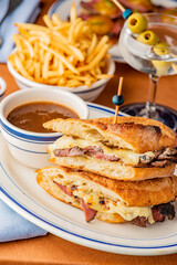 Reuben Sandwich. Classic traditional American sandwich. Pastrami and corned beef on grilled rye bread, melted Swiss cheese, sauerkraut, topped with thousand island dressing served french fries.