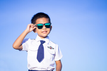 A boy wearing dark glasses in a pilot suit on a blue tone background