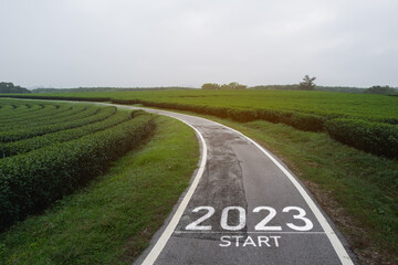 Wall Mural - Happy new year 2023,2023 symbolizes the start of the new year. The letter start new year 2023 on the road in the nature fresh green tea farm mountain environment ecology or greenery wallpaper concept.