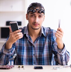 Wall Mural - Young handsome technician repairing mobile phone