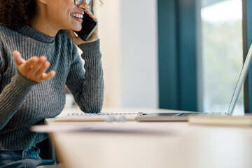 Wall Mural - Close up of woman freelancer working laptop and talking phone while sitting in cozy coworking