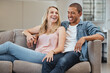 © Delcio F/peopleimages.com - Relax, funny or couple of friends love laughing at joke, story or gossip for entertainment on sofa at home. Interracial, comic or happy woman enjoying quality bonding time and holding hands with man