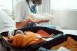 Holiday, packing and woman travel suitcase on a bedroom bed ready for vacation and adventure. Hands holding clothes for journey, trip or cruise with a suitcase, luggage and bag for traveling