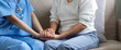 © Natee Meepian - Happy patient is holding caregiver for a hand while spending time together. Elderly woman in nursing home and nurse