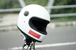 A white motorcycle helmet is mounted on the handlebar of a street-parked motorcycle.
