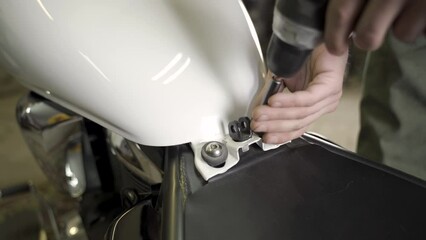Poster - An auto mechanic unscrews the fuel tank fastening nuts with a screwdriver. Close-up.