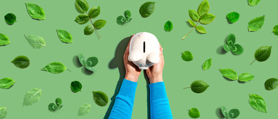 Person holding a piggy bank with green leaves - flat lay