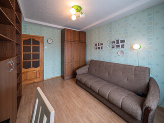 Modern interior of living room in apartment. Empty wooden shelves. Chair and glass table. Cozy sofa.