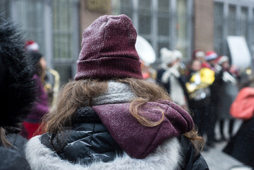 Wall Mural - Portrait on back view of young woman wearing a purple woolen hat covered by the snow in the street