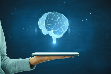 Poster - Close up of female hand holding tablet with glowing human brain hologram on blurry wall background. Neurology research and artificial intelligence concept.